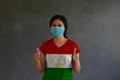 Woman wearing hygienic mask and wearing Tajiks flag colored shirt with thumbs up with both hands on dark wall background