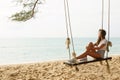 Woman wearing jeans shorts relax on the swing on the beach Royalty Free Stock Photo