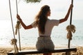 Woman wearing jeans shorts relax on the swing on the beach Royalty Free Stock Photo