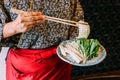 A woman wearing kimono holding cabbage over Sukiyaki vegetables set including cabbage, false pak choi, carrot, shiitake.