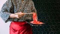 Woman wearing kimono holding rare slice Wagyu A5 beef by chopsticks for boiling in Sukiyaki hot pot