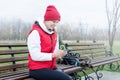 Woman wearing knee brace or orthosis after leg surgery sitting in the park using smartphone