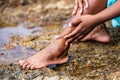 Woman wearing light blue outfit sitting on the beach rock splashing her feet Royalty Free Stock Photo