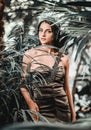 Woman wearing long elegant dress and tiara on head posing surrounded by lush tropical trees Royalty Free Stock Photo