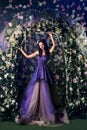 Woman wearing long purple dress posing in the flowered garden Royalty Free Stock Photo