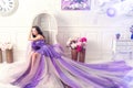 Woman wearing long purple dress posing in studio interior Royalty Free Stock Photo