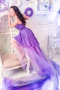 Woman wearing long purple dress posing in studio interior Royalty Free Stock Photo