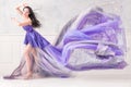 Woman wearing long purple dress posing in studio interior Royalty Free Stock Photo