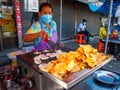 Woman wearing mask cooking Khanom Buang Thai or a kind of filled pancake