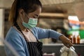 A woman wearing a mask is pouring coffee out of the jug Royalty Free Stock Photo