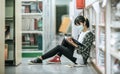 A woman wearing masks is sitting reading a book in the library