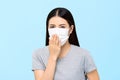 Woman wearing medical face mask coughing isolated on light blue background