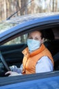 Woman wearing medical mask in car, orange waistcoat, Caucasian driver