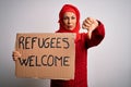 Woman wearing muslim hijab asking for immigration holding welcome refugees message with angry face, negative sign showing dislike Royalty Free Stock Photo