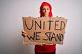 Woman wearing muslim hijab asking for union holding banner with united stand message cover mouth with hand shocked with shame for