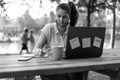 Woman wearing open protective face mask using laptop outdoors - Female solopreneur taking notes while working in alternative Royalty Free Stock Photo