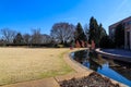 A woman wearing a pink sweater sitting on yellow winter grass having lunch with her two daughters near a small pond Royalty Free Stock Photo