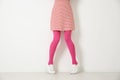 Woman wearing pink tights near white wall