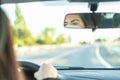 Woman wearing protective face mask while driving car. Reflection in mirror Royalty Free Stock Photo