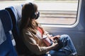 Woman wearing protective face mask and headphones travelling by traing. Royalty Free Stock Photo