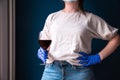 Woman wearing protective mask and blue gloves in her home and drinking red wine, self isolated for Coronavirus Covid-19, sad and Royalty Free Stock Photo