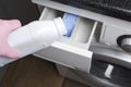 Woman wearing protective pink gloves and pouring liquid detergent into the washing machine.Household routines