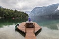 Woman wearing purple hoodie watching tranquil overcast morning scene at lake Bohinj, Alps mountains, Slovenia. Royalty Free Stock Photo