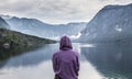 Woman wearing purple hoodie watching tranquil overcast morning scene at lake Bohinj, Alps mountains, Slovenia. Royalty Free Stock Photo