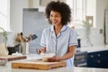 Woman Wearing Pyjamas Making Morning Pancakes In Kitchen At Home