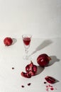 Vertical image.Old fashioned glass, pomegranates, alcohol drink on the white table against bright wall