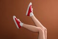 Woman wearing red classic old school sneakers on brown background, closeup Royalty Free Stock Photo