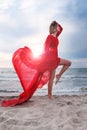 Woman wearing red flying dress on a beach. Female energy