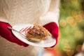 Woman Wearing Red Mittens Holding Plate of Pecan Pie with Peppermint Candy Against Decorated Tree and Lights Royalty Free Stock Photo