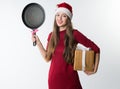 Woman wearing red santa claus hat with gift frying pan Royalty Free Stock Photo