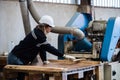 Woman wearing safety uniform and hard hat working on wood sanding electric machines at workshop manufacturing wooden. Female Royalty Free Stock Photo