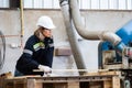 Woman wearing safety uniform and hard hat working on wood sanding electric machines at workshop manufacturing wooden. Female Royalty Free Stock Photo