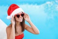 Young woman wearing Santa Claus hat near swimming pool. Christmas vacation Royalty Free Stock Photo