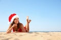 Woman wearing Santa hat and bikini on beach, space for text. Christmas vacation Royalty Free Stock Photo