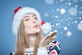 Woman wearing Santa hat blowing at open hand palm with snow Royalty Free Stock Photo