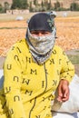 Woman wearing a scarf on her face, at a field where pears are being prepared and dried in the sun