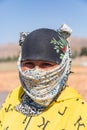 Woman wearing a scarf on her face, at a field where pears are being prepared and dried in the sun