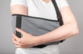 Woman wearing sling to support painful elbow. Overuse, intensive training, tendinitis consequences. Healing process of Royalty Free Stock Photo