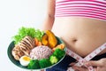 Woman wearing sport bra with belly fat and measuring tape holding a dish of healthy food. Healthy and Diet concept Royalty Free Stock Photo