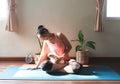 Woman wearing sportwear sitting on yoga mat in morning sunlight playing with her Chihuchua dog on her lap Royalty Free Stock Photo