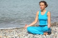 Woman wearing sporty clothers is meditate on sea