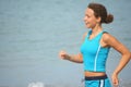 Woman wearing sporty clothers is running near sea