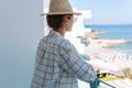 Woman wearing straw hat enjoy view from balcony of beachfront hotel or apartment