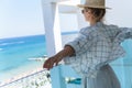 Woman wearing straw hat enjoy view from balcony of beachfront hotel or apartment