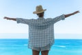 Woman wearing straw hat enjoy view from balcony of beachfront hotel or apartment