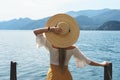 Woman is wearing straw hat looking on the beautiful lake